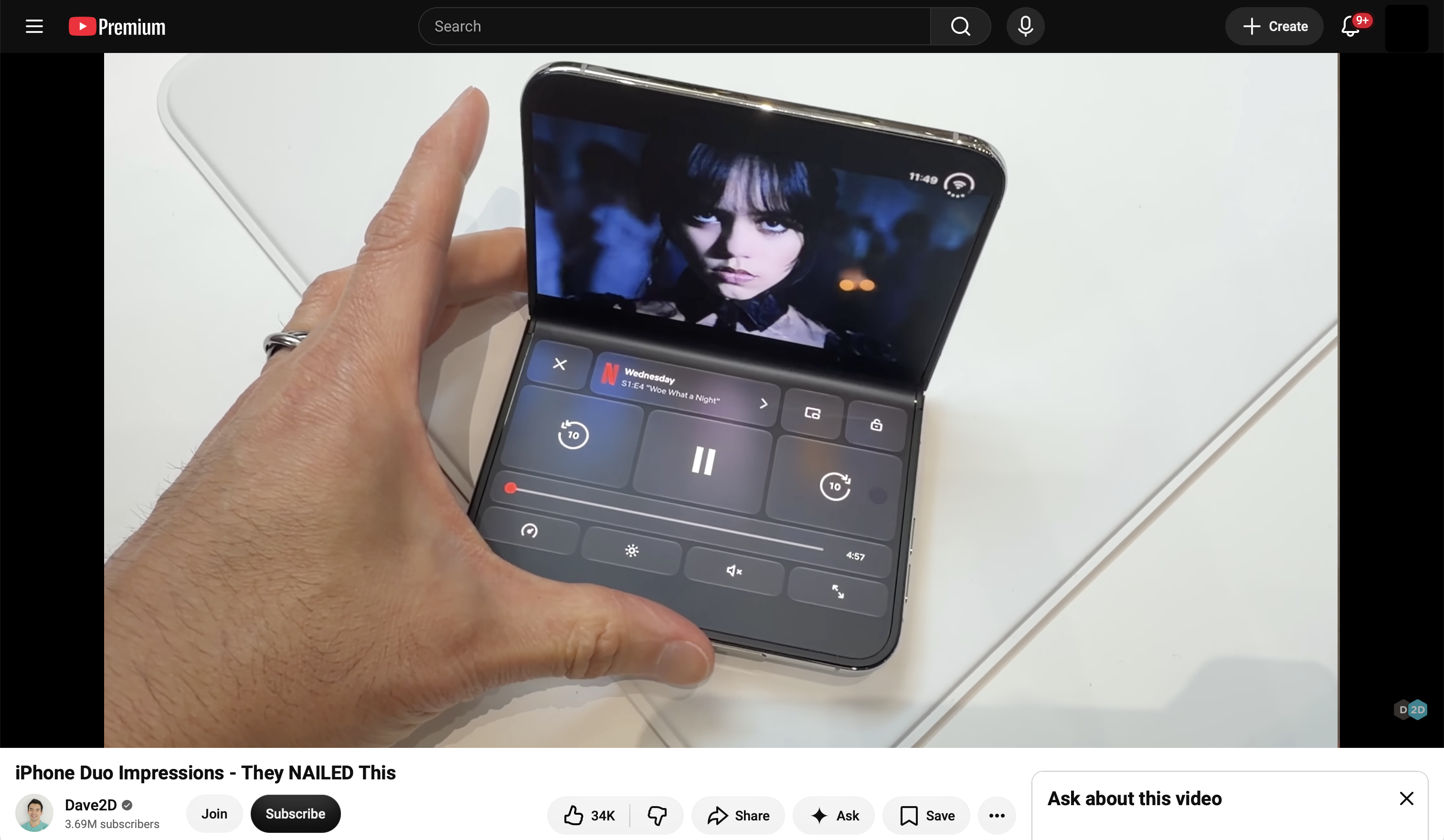 A hand holding a partially folded iPhone Duo playing Netflix, with video on the top half and large controls on the bottom half